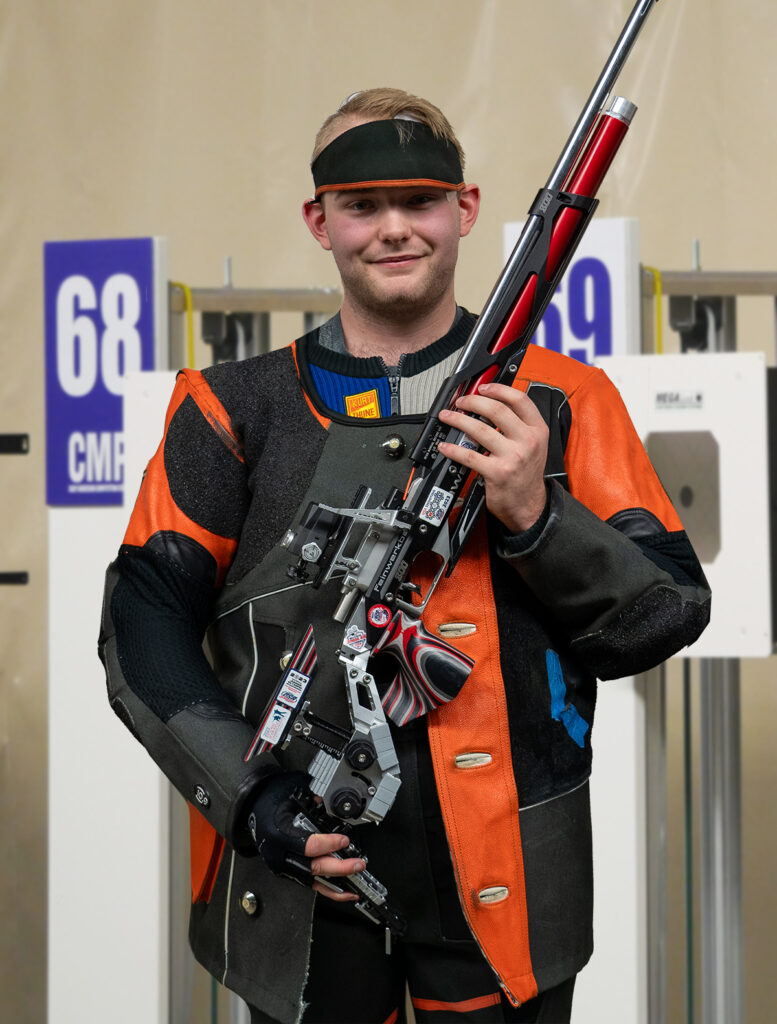 Sam poses with his precision air rifle after the start-from-zero Final. Sam finished the qualification round in fifth place and secured the Championship title during the Final.