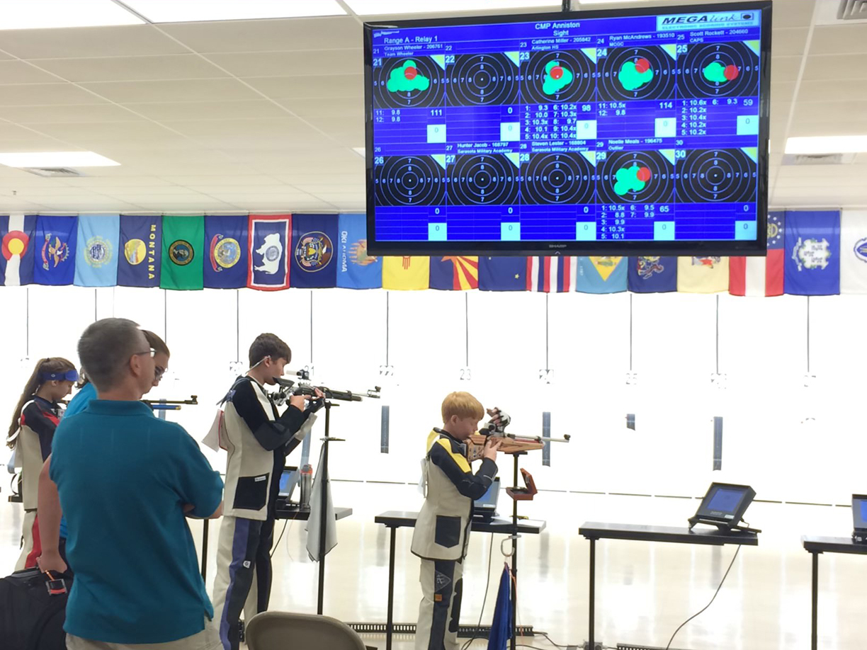 At CMP’s Summer Air Rifle Camps, Scott (in yellow) was initially acquainted with his future National Team Coach, Dan Durben (foreground), who was camp director.