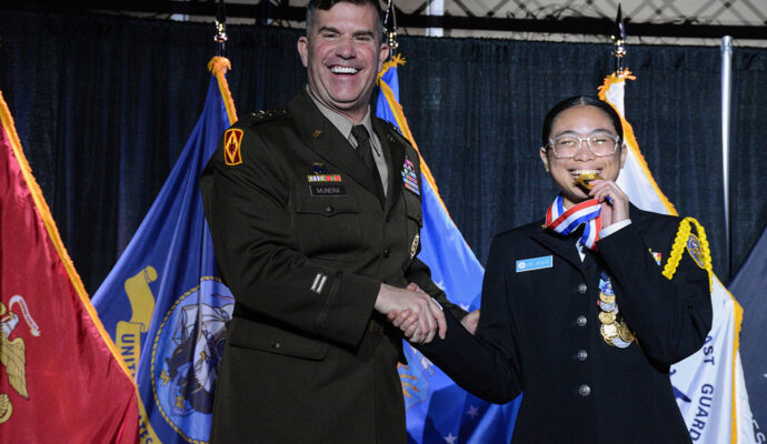 Danjela de Jesus playfully bit her precision gold medal as she received it onstage at the 2023 JROTC Nationals banquet.